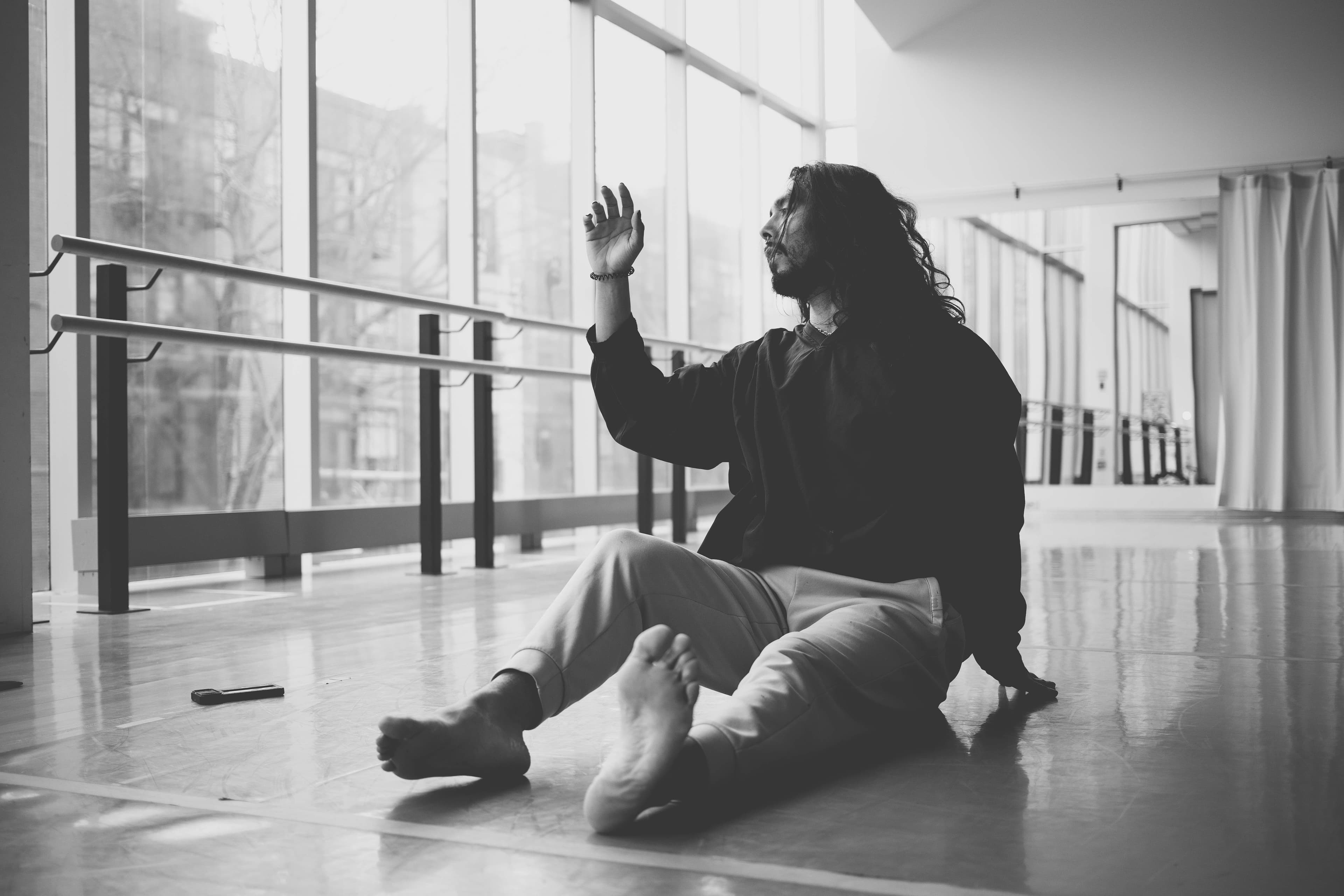 Niki seated on the studio floor, one hand raised toward the window