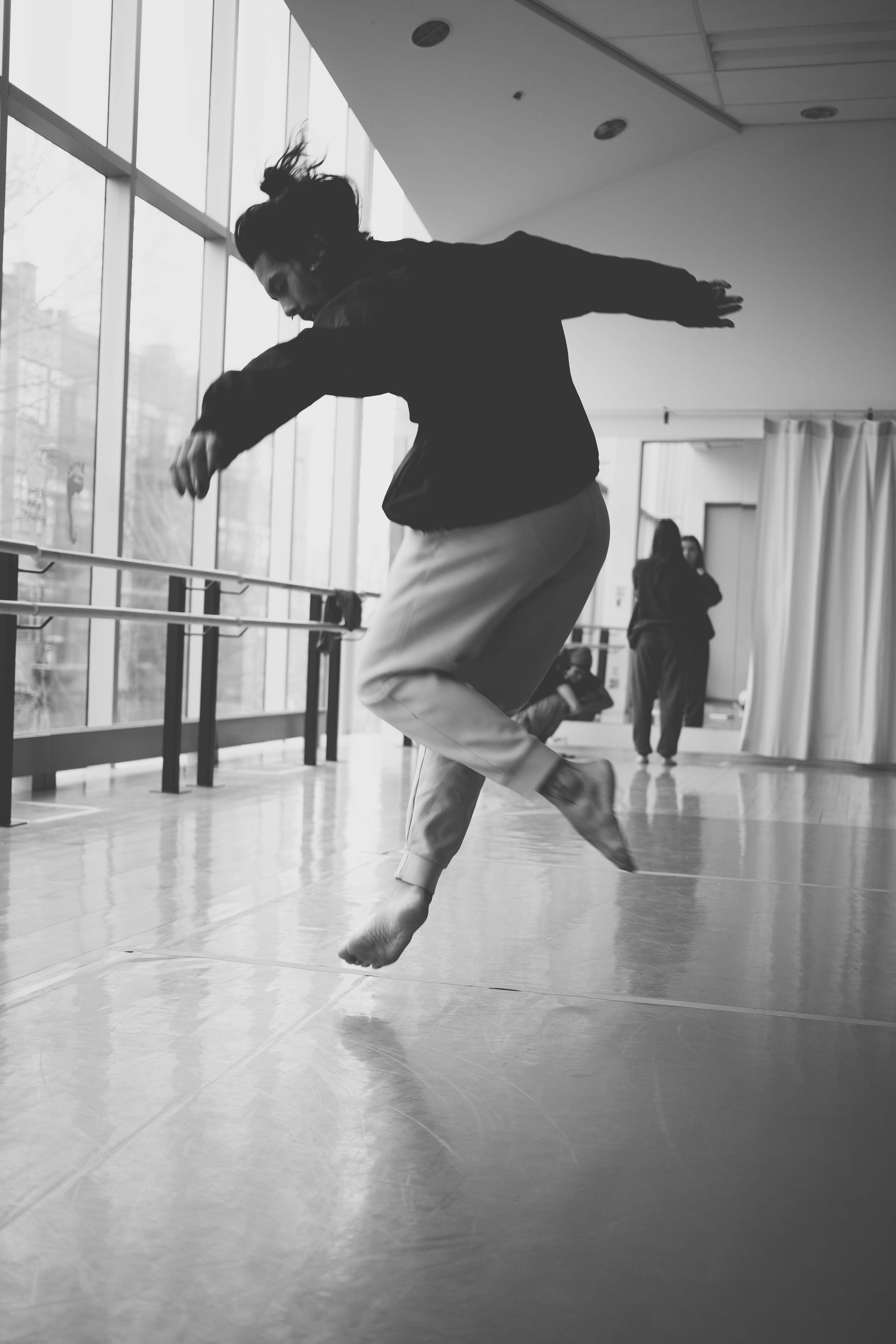 Niki jumping with arms spread in a studio with tall windows