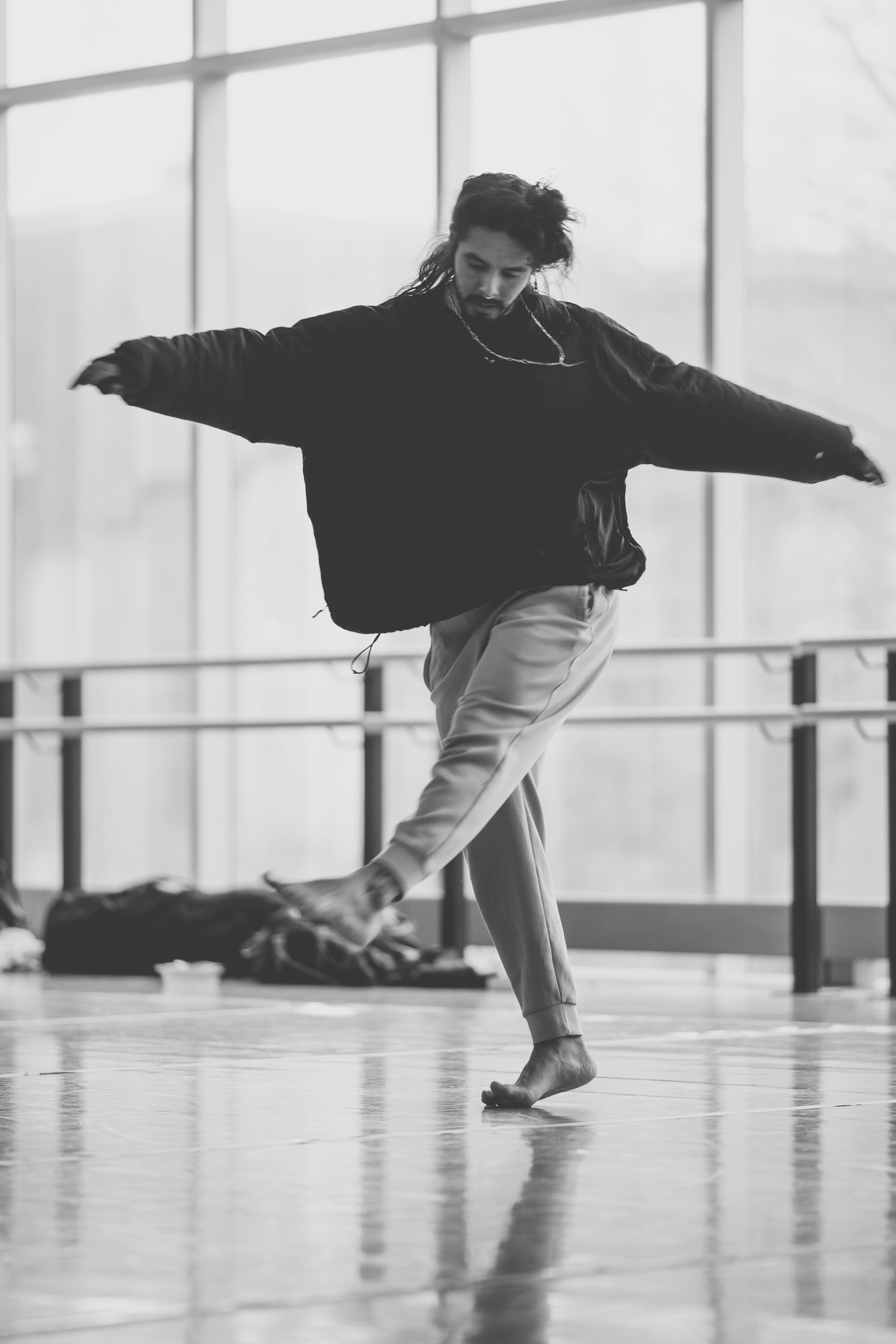 Niki balancing on one foot, arms open, in a dance studio