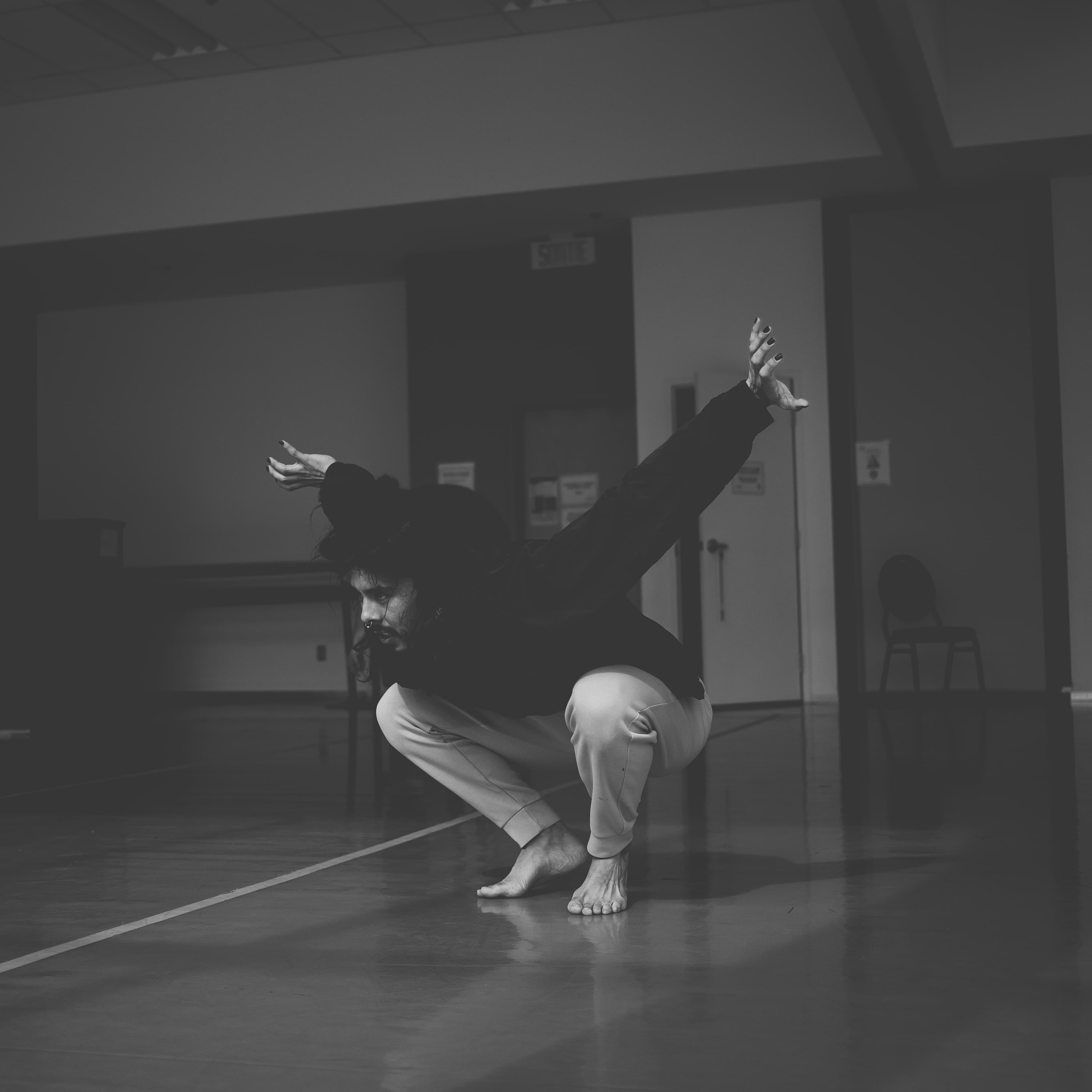 Niki in a deep crouch with one arm extended upward