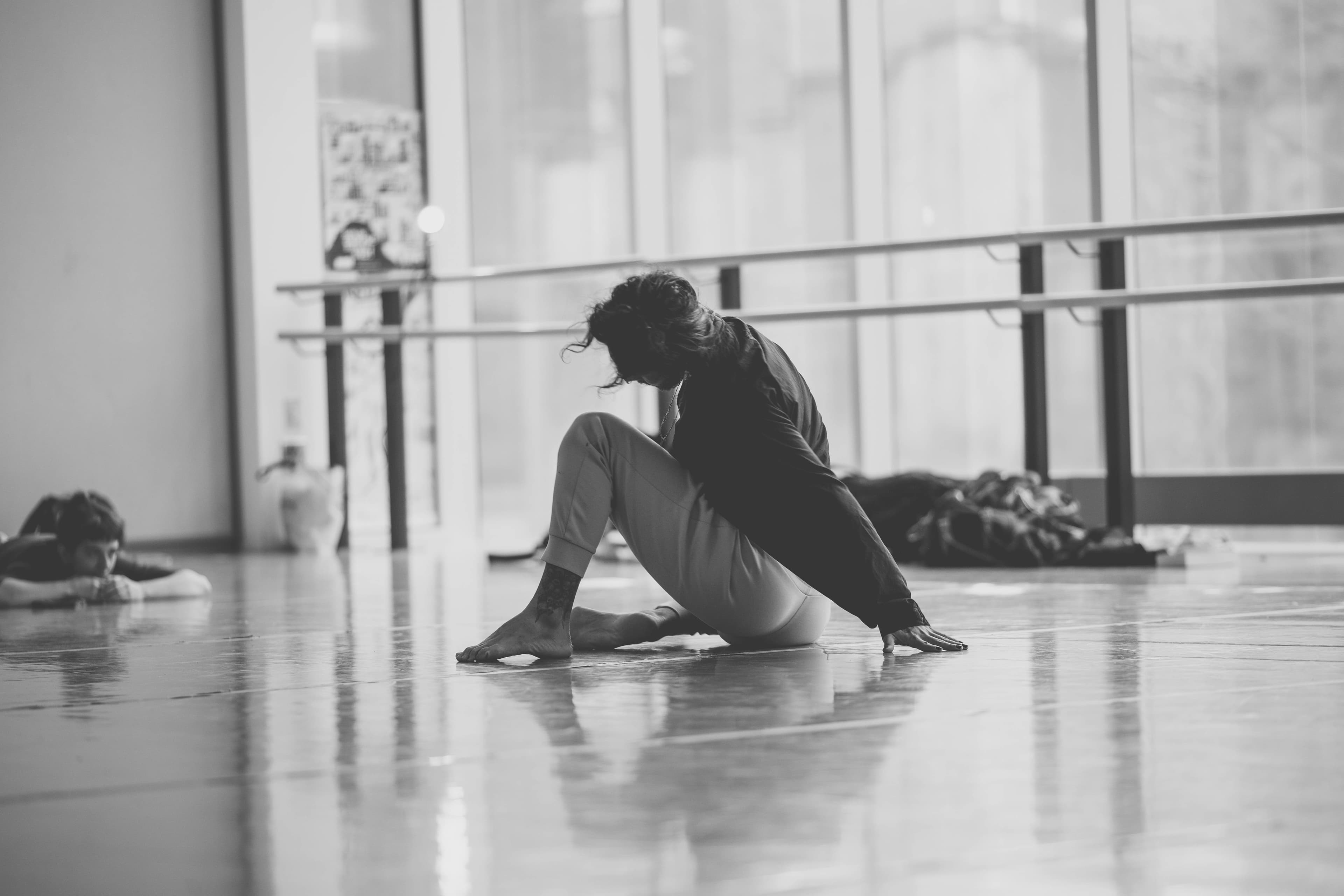 Niki seated on the floor, head lowered, in a bright studio
